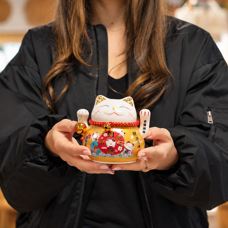 Keramik-Glückskatze (Maneki-neko) mit beweglicher Winkehand – Gold auf Kissen (Batterie nicht enthalten)